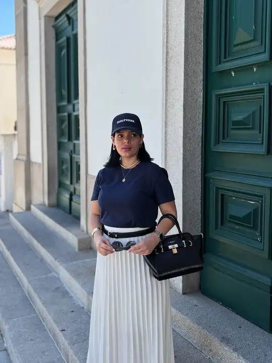 18 Preppy Outfits for Women Over 40 9 Navy Tee, Baseball Cap, and a Pleated White Maxi Skirt