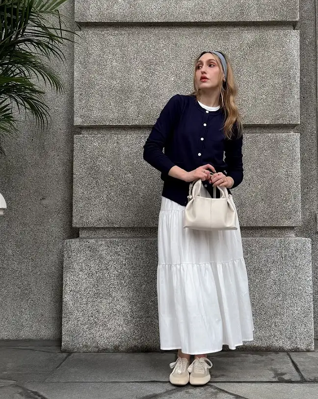 18 Preppy Outfits for Women Over 40 8 Navy Cardigan, White Tiered Skirt, and Ballet Sneakers