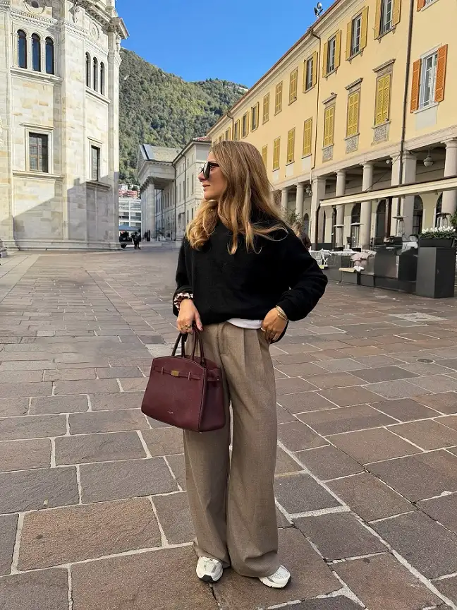 17 Italy Vacation Outfits for Women Over 40 That Look Effortlessly Chic 9 Black Fuzzy Sweater with Taupe Pleated Trousers