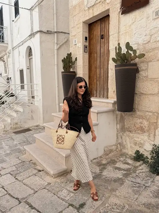 17 Italy Vacation Outfits for Women Over 40 That Look Effortlessly Chic 6 Black Linen Vest with a Polka Dot Satin Skirt