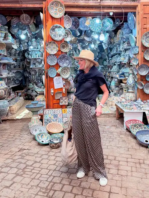 16 Spring Transitional Outfits Over 40 (Winter-to-Spring) 12 Printed Wide Trousers With a Black Tee and Straw Hat