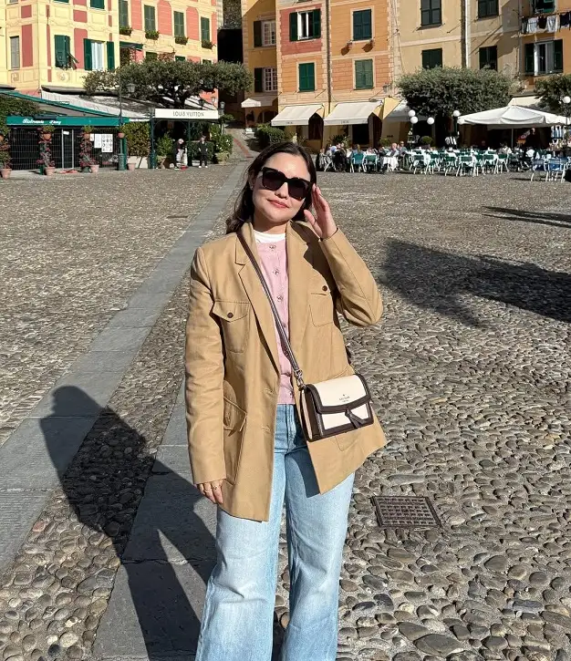 17 Italy Vacation Outfits for Women Over 40 That Look Effortlessly Chic 8 Camel Blazer, Pink Cardigan, and Light Wash Jeans