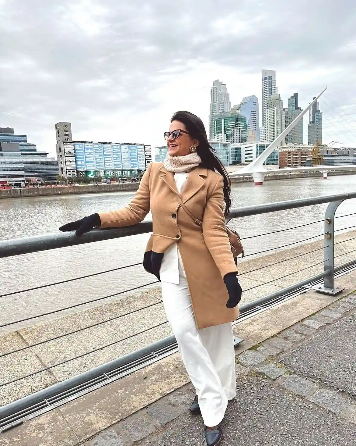 19 Winter Vacation Outfits Over 40 (Warm Getaways) 17 16. Camel Coat and White Pants by the Water