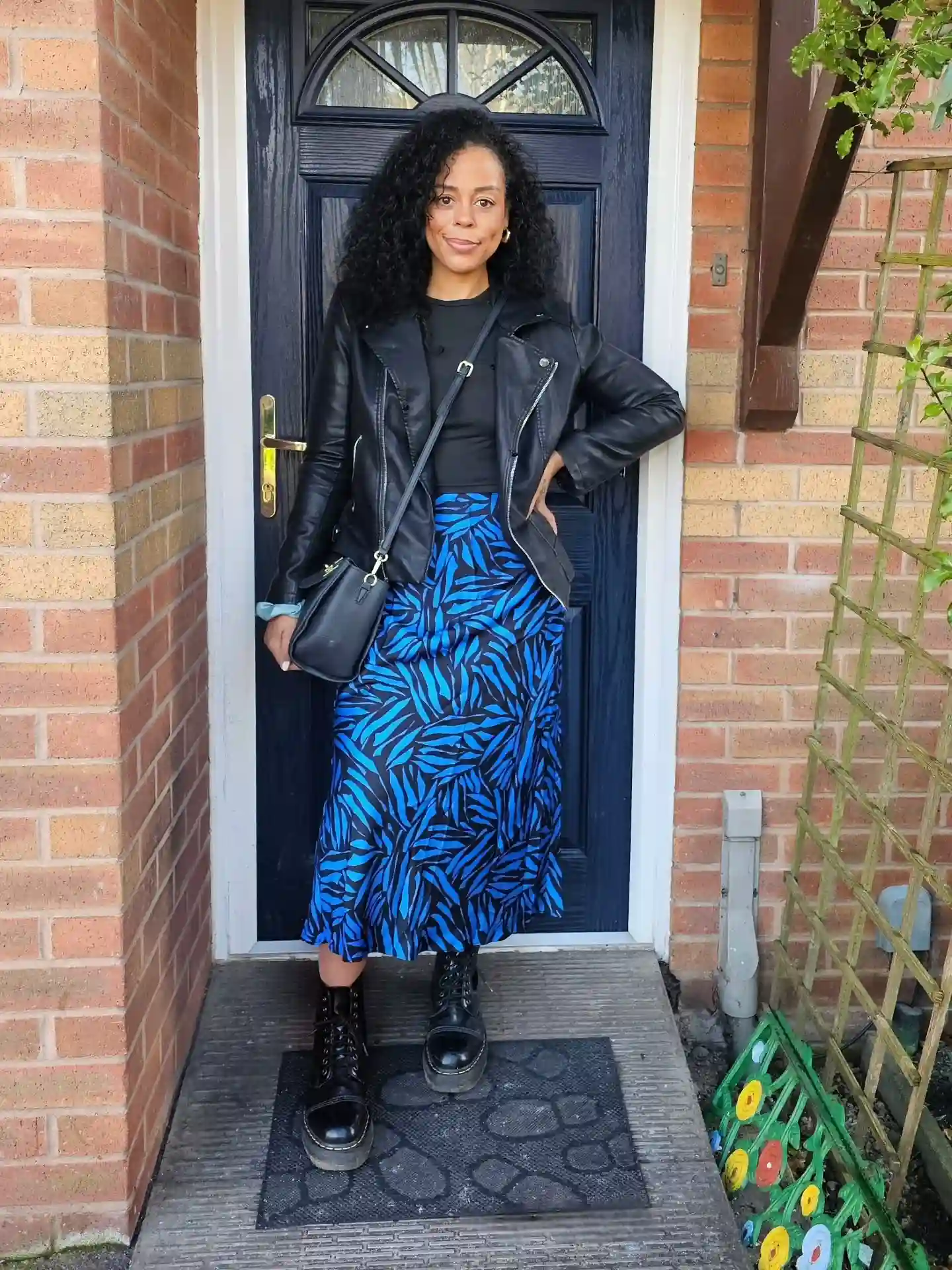 15 Leather Jacket Outfits for Women Over 40 That Actually Work 12 11. Black Moto Jacket with Cobalt Print Skirt