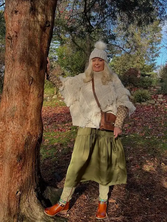 20 Chic Winter Outfits for Women Over 40 That Aren't Frumpy 10 Fringed Knit Poncho With a Satin Skirt