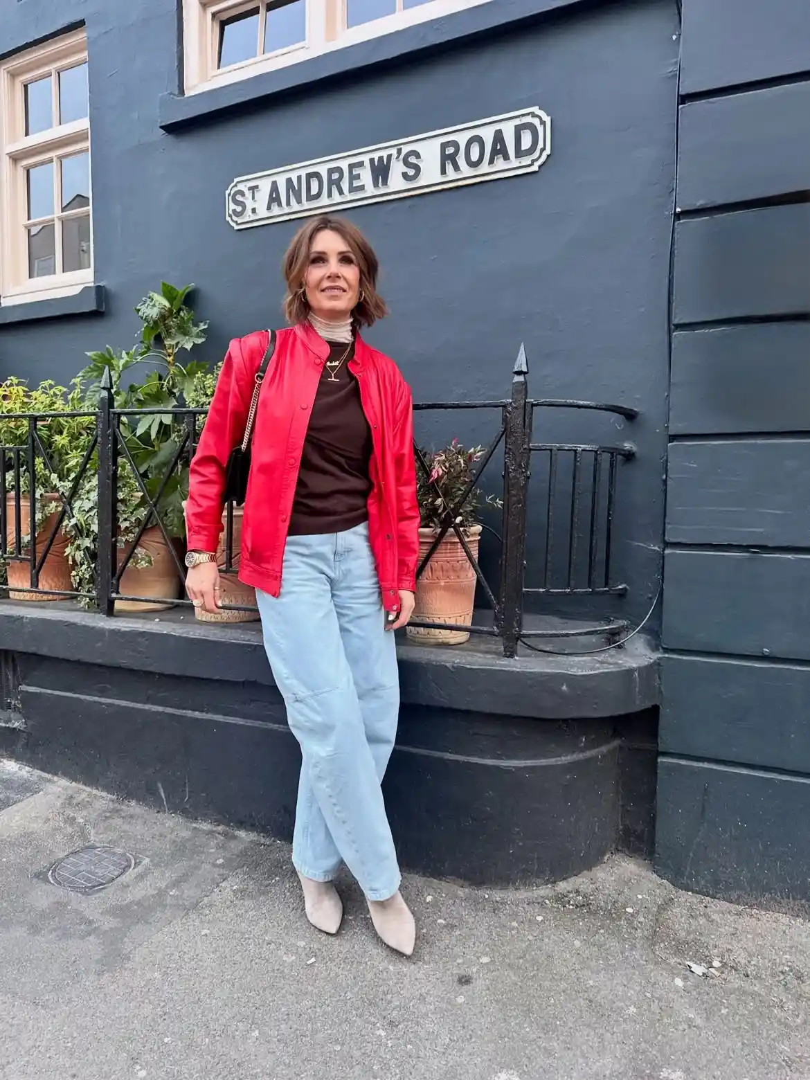 15 Leather Jacket Outfits for Women Over 40 That Actually Work 9 8. Bold Red Jacket with Light Wash Jeans
