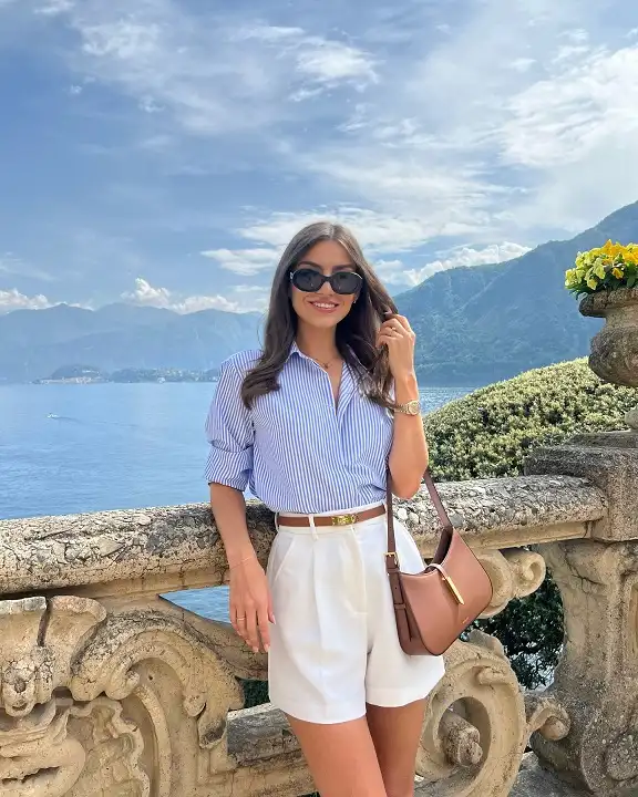 15 European Vacation Outfits for Women Over 40 2 Blue Striped Shirt with White Pleated Shorts