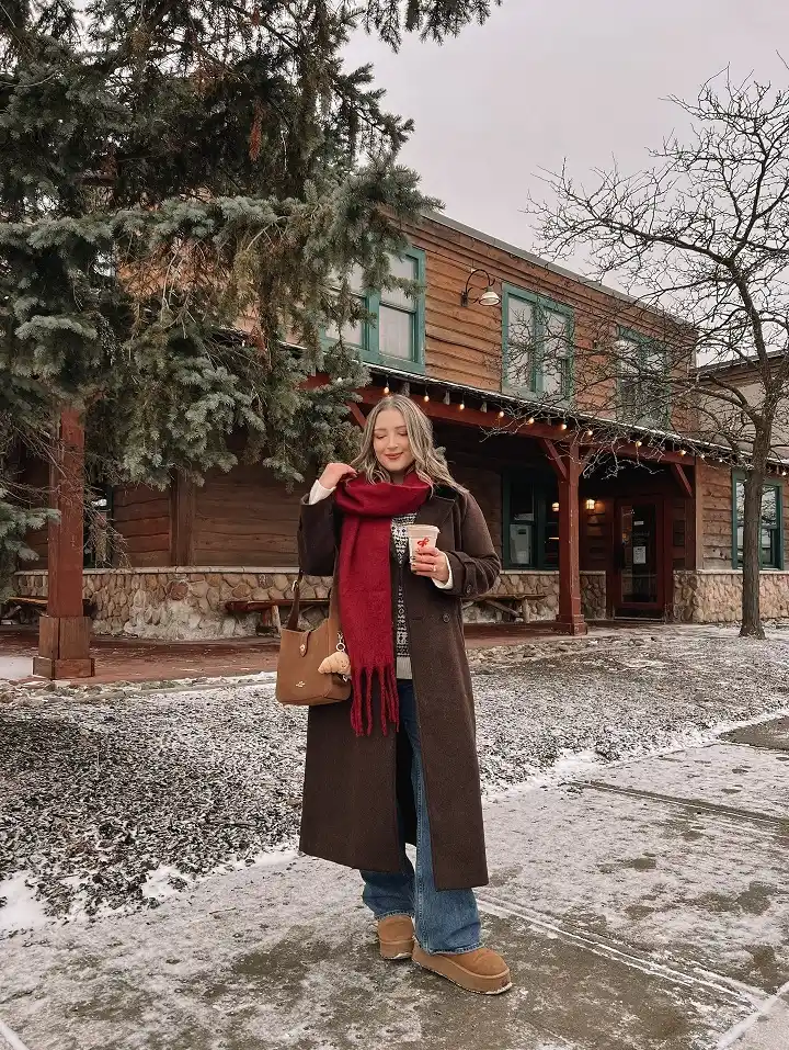 18 Winter 2026 Outfits for Women Over 40 13 A Long Brown Coat With a Red Fringe Scarf for Festive Holiday Days