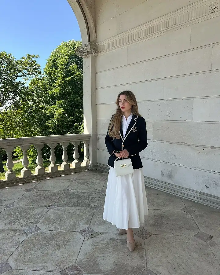 18 Preppy Outfits for Women Over 40 7 Navy Piped Blazer Over a White Midi Skirt