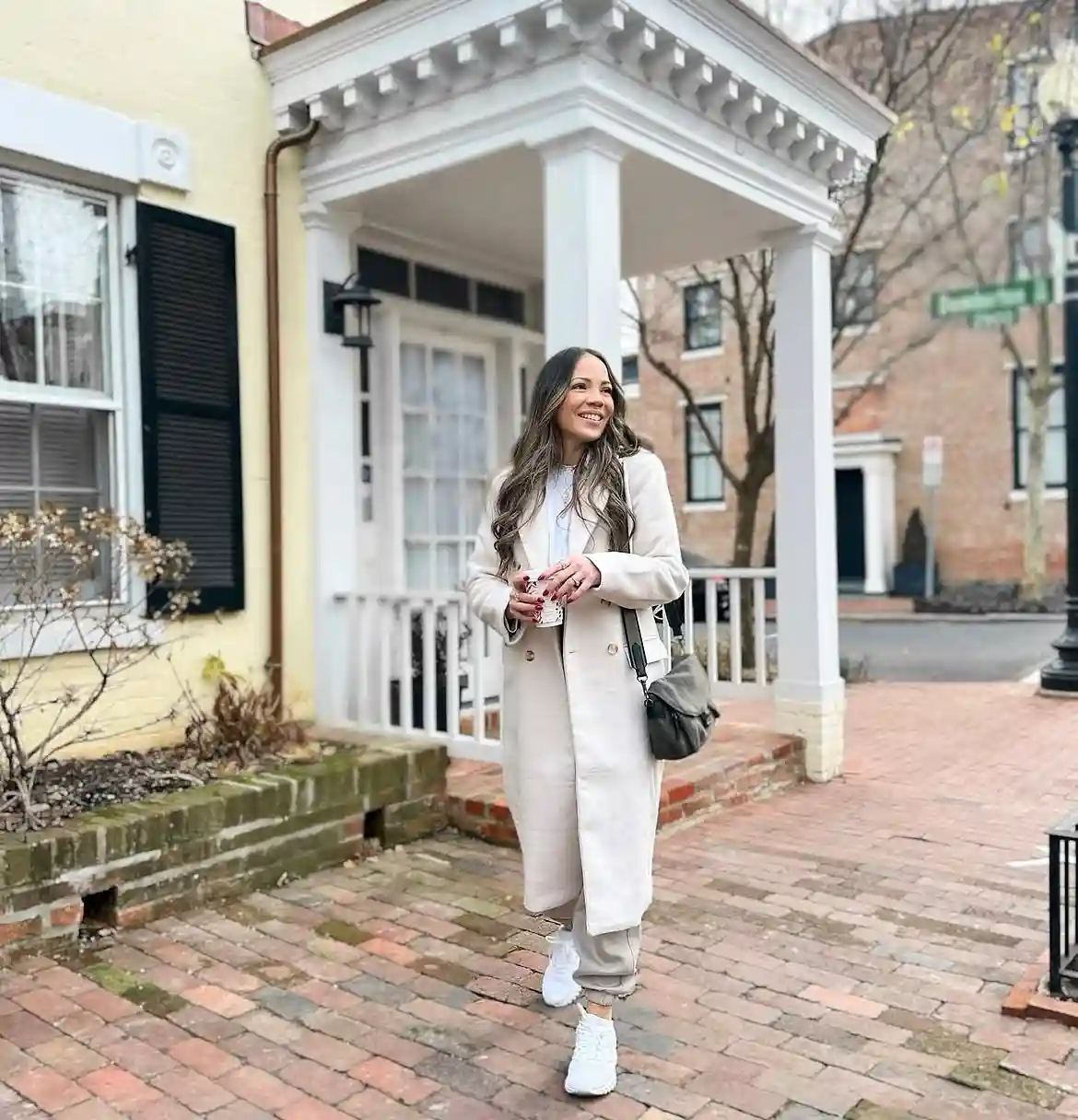 19 Winter Vacation Outfits Over 40 (Warm Getaways) 4 3. Long Cream Coat With Jogger Pants and White Sneakers
