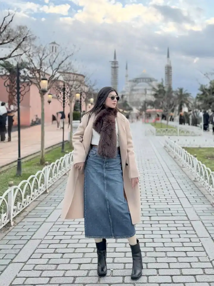 18 Winter 2026 Outfits for Women Over 40 11 A Denim Midi Skirt With a Long Coat and Faux Fur Scarf for Winter Sightseeing